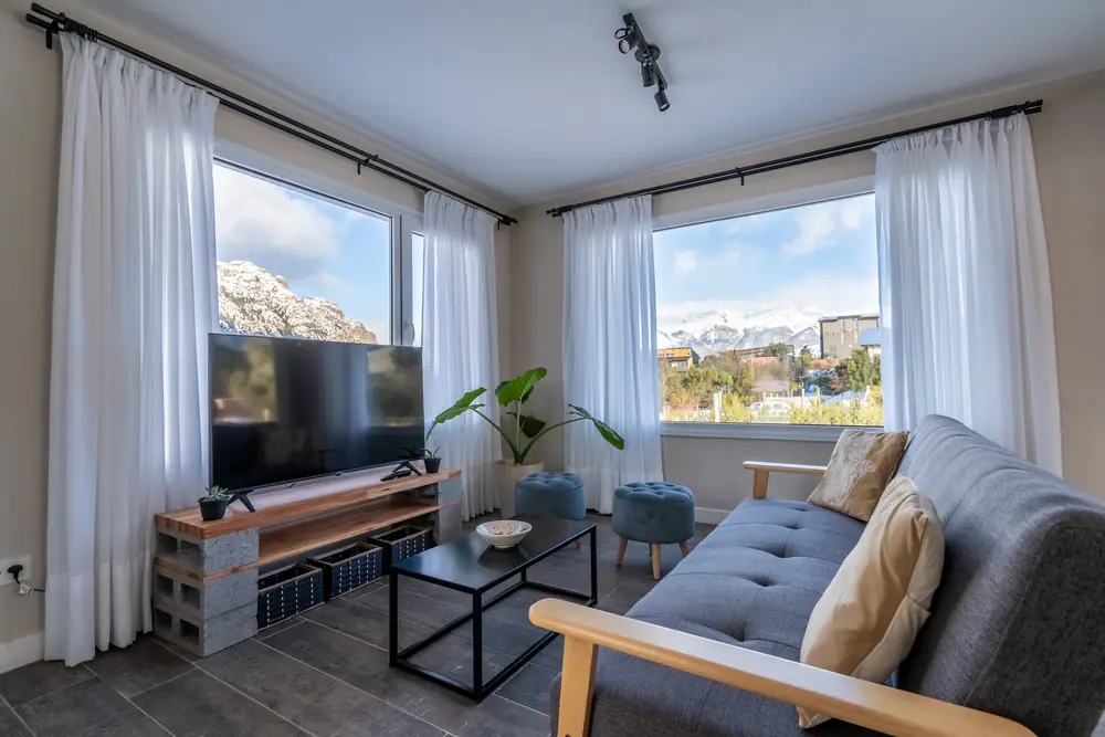 Living con sofá y TV frente al ventanal